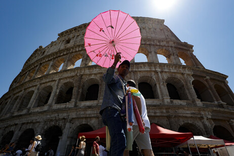 Vendedor se protege do calor no Coliseu de Roma, na Itália