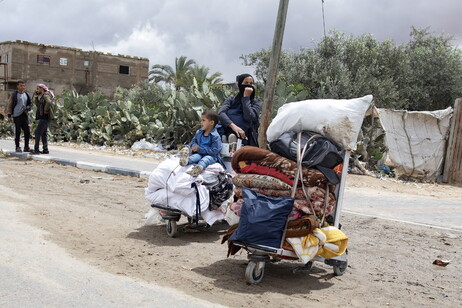 Mulher e criança palestinas fogem após ordem de evacuação no leste de Rafah