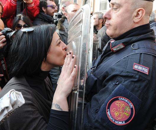 Una ragazza bacia lo scudo di un carabiniere nel corso delle proteste durante la visita di Renzi