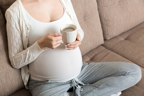 Una donna in gravidanza beve una tazza di caffè. Attestazione: Mykola Sosiukin - iStock