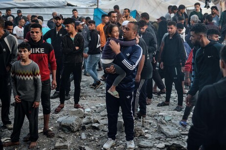 Homem segura criança chorando após ataque israelense contra escola em Gaza