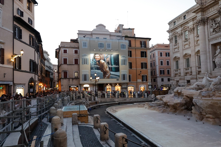 Fontana di Trevi senza acqua per il restauro, turisti lanciano monete in una vasca