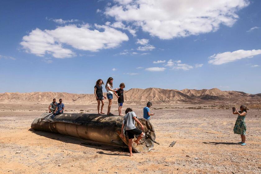 Pessoas em cima dos restos de um míssil iraniano no deserto de Negev, perto de Arad, após um ataque