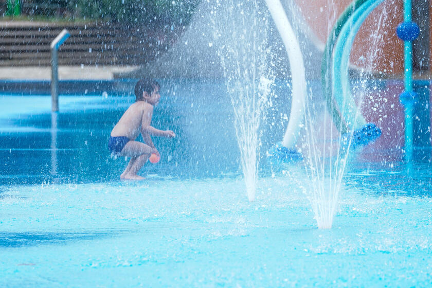 Un niño juega con chorros de agua en una plaza