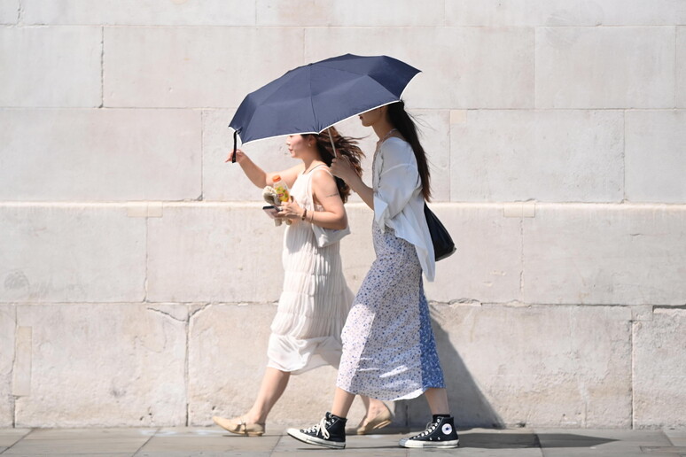 Pedestres se protegem contra calor em Londres, Reino Unido © ANSA/EPA