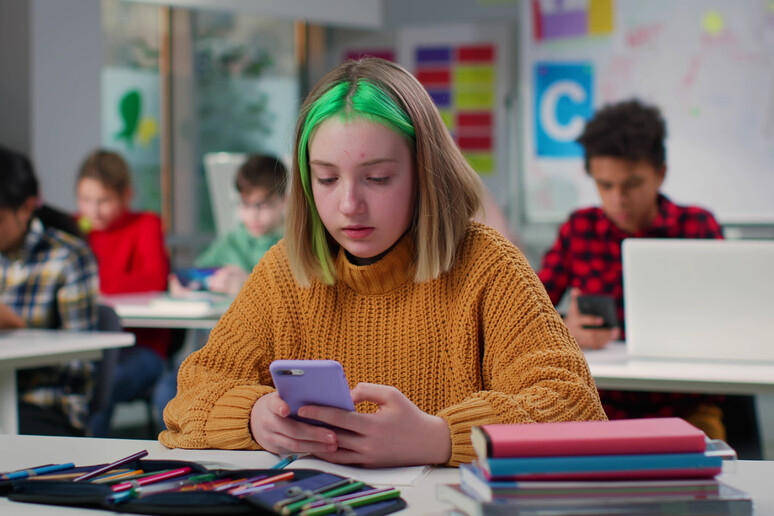 Teenager con lo smartphone in classe foto iStock. - RIPRODUZIONE RISERVATA