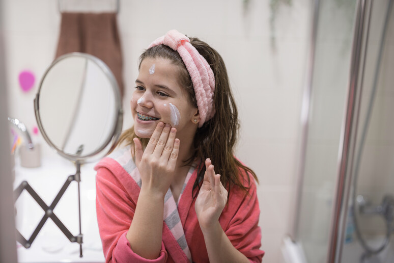 Una giovane prova una crema sul viso foto iStock. - RIPRODUZIONE RISERVATA