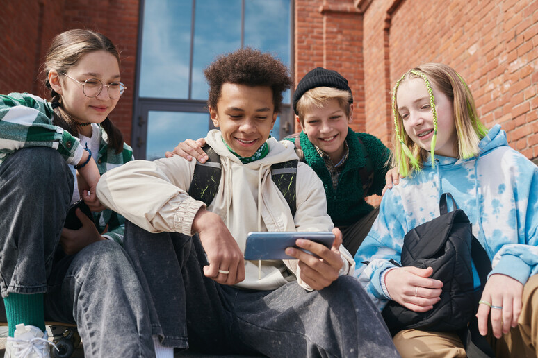 Adolescenti guardano video sullo smartphone foto iStock. - RIPRODUZIONE RISERVATA