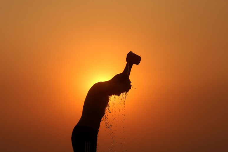 Trabalhador se refresca contra calor na cidade de Jammu, na Índia © ANSA/AFP